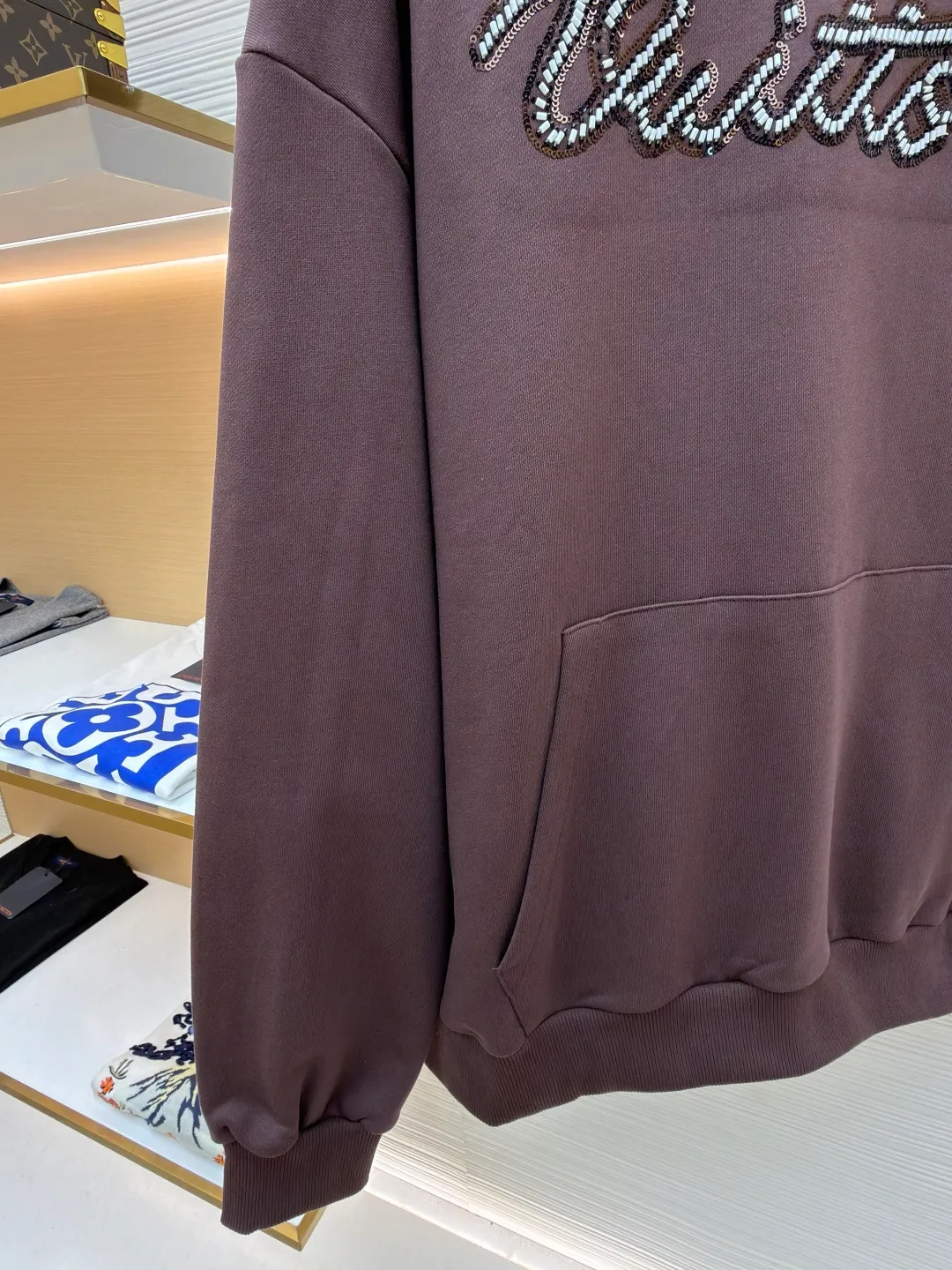 LOUIS VUITTON beaded embroidered letter hooded sweatshirt ●Item number: 1682118-A60 ●Material: pure cotton fish scale base fabric ●Technology: Pearl embroidery production ●Color: brown ●Version: fitted version ●Weight: about 830 grams ●Size: S-M-L-XL ●Description: The fabric is made of 26S double yarn + 10S fish scale bottom brushed fabric, weight 380g, with 21S double yarn 2*2 rib, weight 380g. This kind of fabric is treated with fleece to form a layer of soft and plump fluff on the inside; the improved fish scale knitting method forms a delicate concave and convex texture on the bottom surface, similar to the arrangement of fish scales. Effectively increases the air storage layer and improves thermal insulation performance. The front of the fabric is smooth and smooth, while the back is soft and waxy. It has excellent moisture absorption, breathability, wrinkle resistance and drape, and is thicker and crisper than ordinary sweatshirt materials. It gives clothes excellent warmth retention, breathability and skin-friendly touch. The Vuitton script on the chest is embroidered with beads. During the embroidery process, tiny beads are fixed on the fabric together with embroidery thread. The direct characteristics brought by this process are a strong three-dimensional sense, a unique sense of weight and a reflective effect that changes with the light. The overall wiring is straight and delicate, the fabric is comfortable and soft, and the color is consistent without color difference. It can be matched with the same style to create a fashionable look and control various occasions. Customized accessories, complete with three standards, same style for men and women!